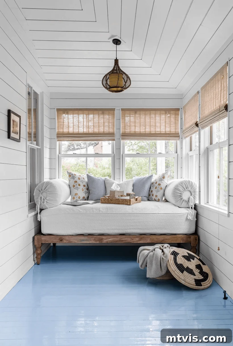 Screened Porch Retreats: Designs for Blissful Outdoor Living 7 A white sun porch with blue floor with daybed against the narrow back wall.