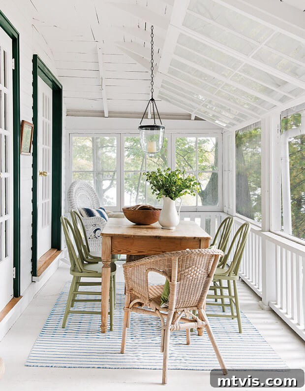 Screened Porch Retreats: Designs for Blissful Outdoor Living 8 A screened-in porch with vintage dining table and olive green chairs, with a white slanted ceiling and dark green door trim.