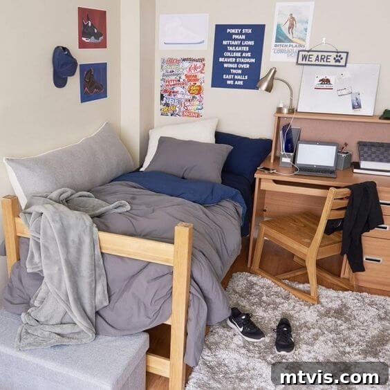 dorm room with messy gray covers and desk with laptop, highlighting a study area