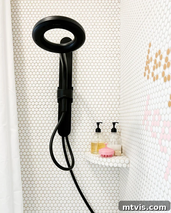 Newly installed black shower head with white penny tiles in a renovated girl's bathroom, showcasing a successful tile-over-tile project