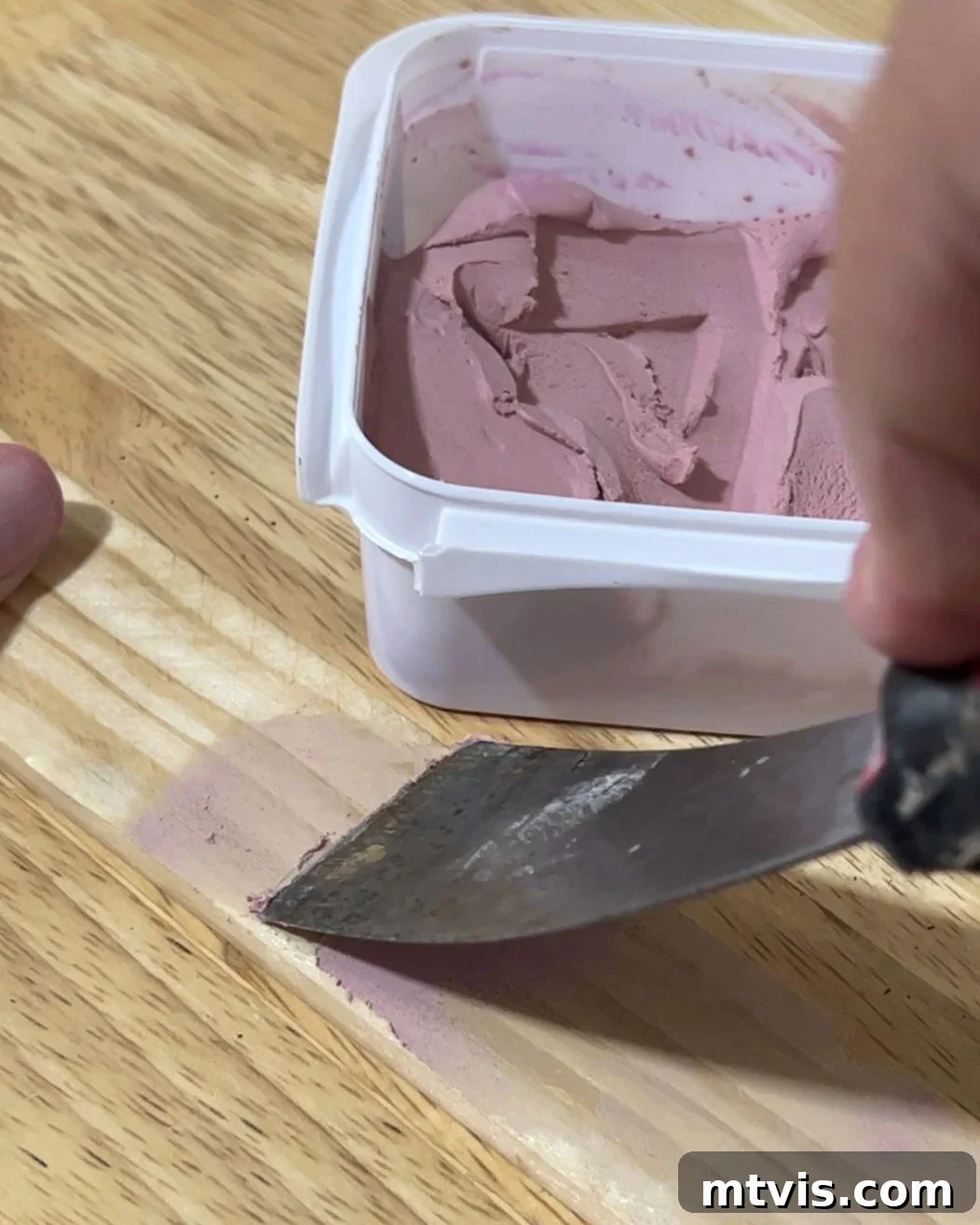 Handmade Magnetic Poster Rails 7 Applying pink DAP Plastic Wood-X wood filler to a rough lattice strip to create a smooth surface for DIY magnetic poster hangers.