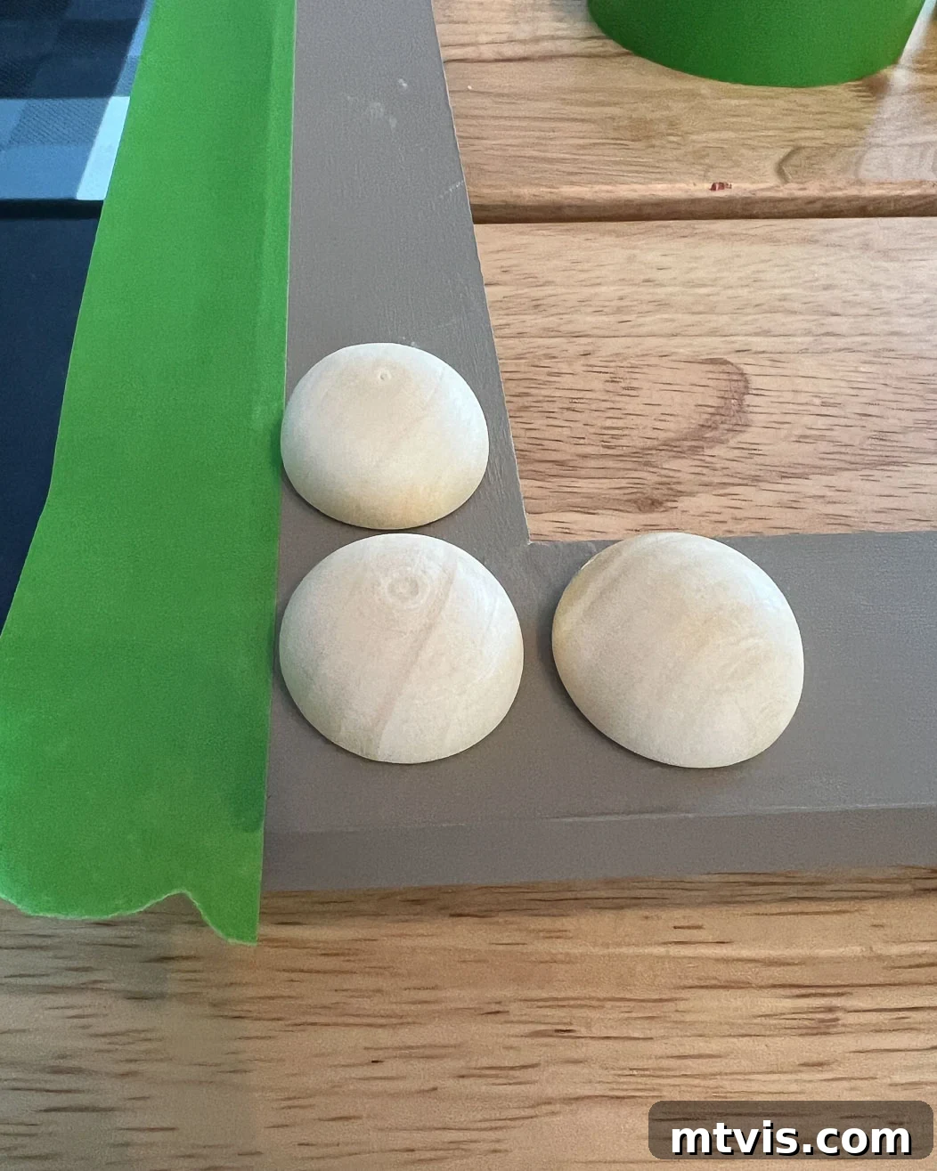 Strategically gluing wooden half balls onto the DIY TV frame, starting with the corners