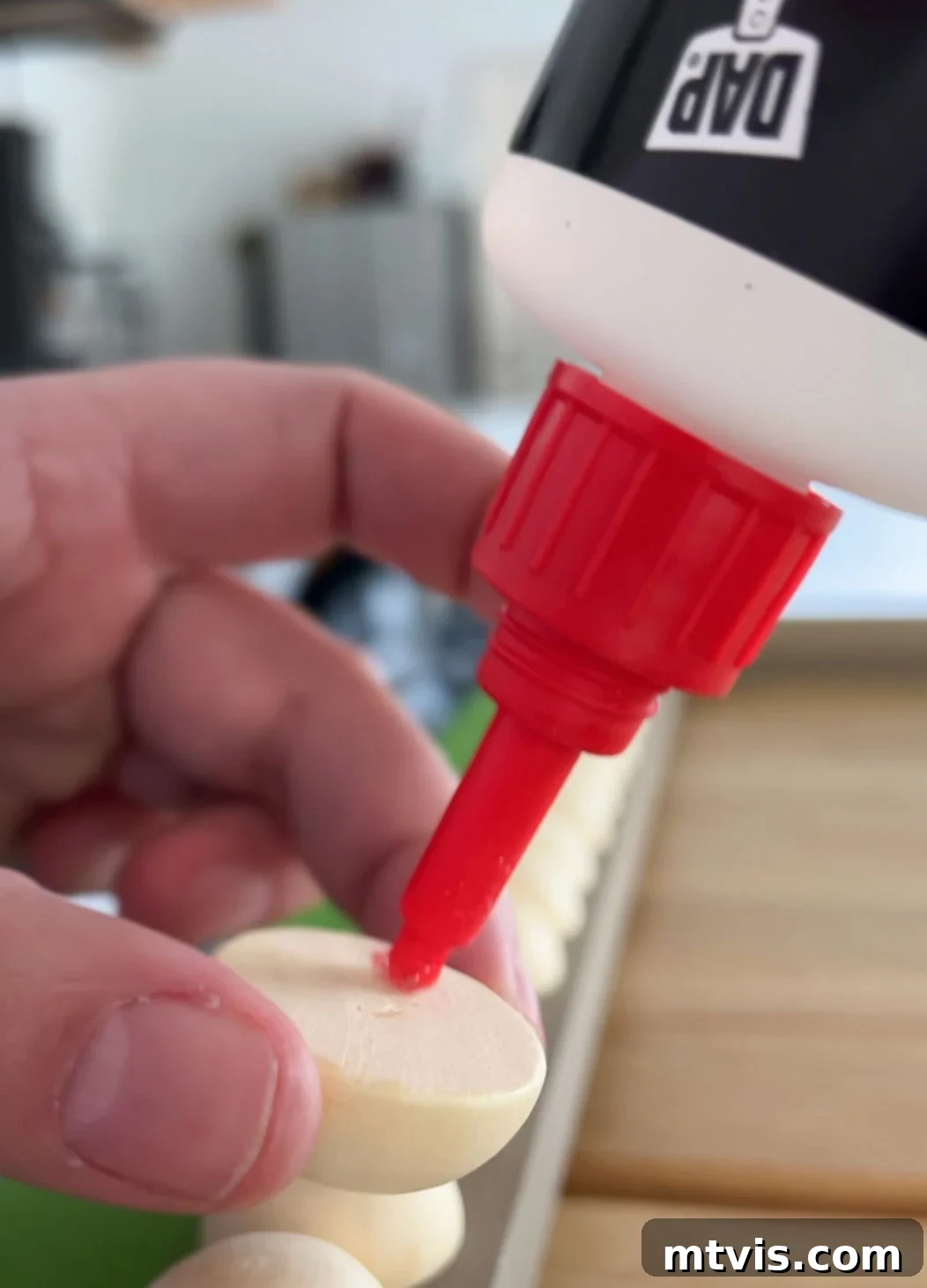 Close-up of gluing wooden half balls onto the DIY TV frame, guided by painter's tape for alignment