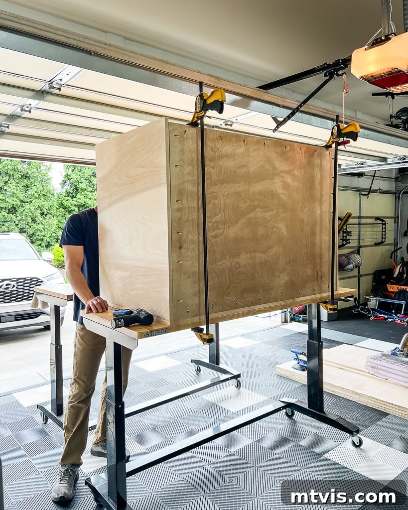 A dedicated individual carefully assembling a DIY dog crate made of plywood, using clamps to secure panels during the construction process.