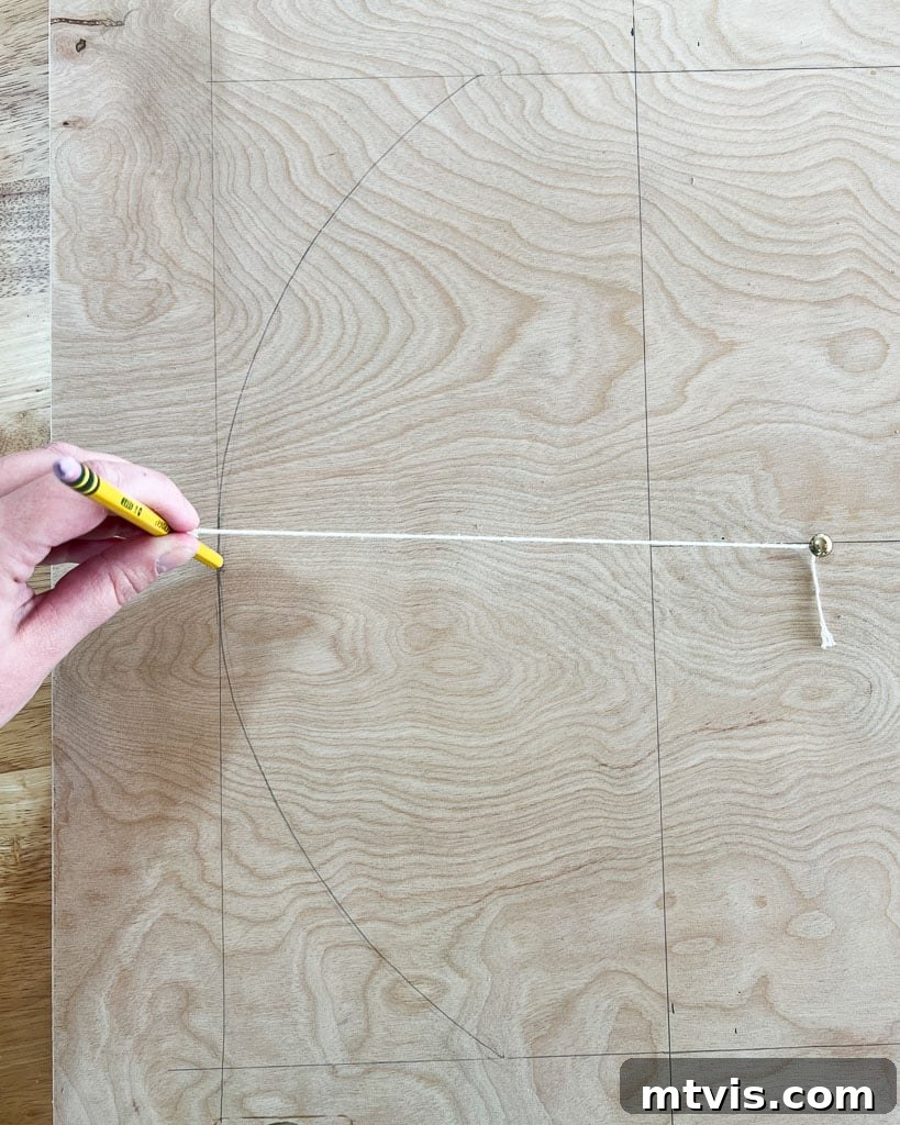 A detailed process of drawing an arch shape onto plywood using a string and pencil attached to a nail, ensuring a perfect curve for the DIY dog crate door.