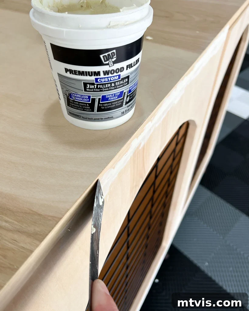 A person meticulously filling small gaps along the frame of a wooden DIY dog crate with wood filler, ensuring a smooth and finished surface.