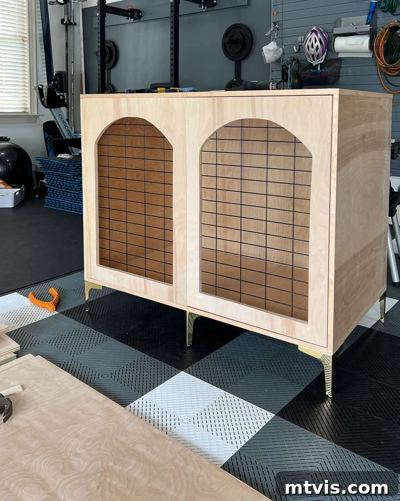A fully assembled DIY dog crate that resembles a piece of furniture, with its door installed and ready for finishing touches.