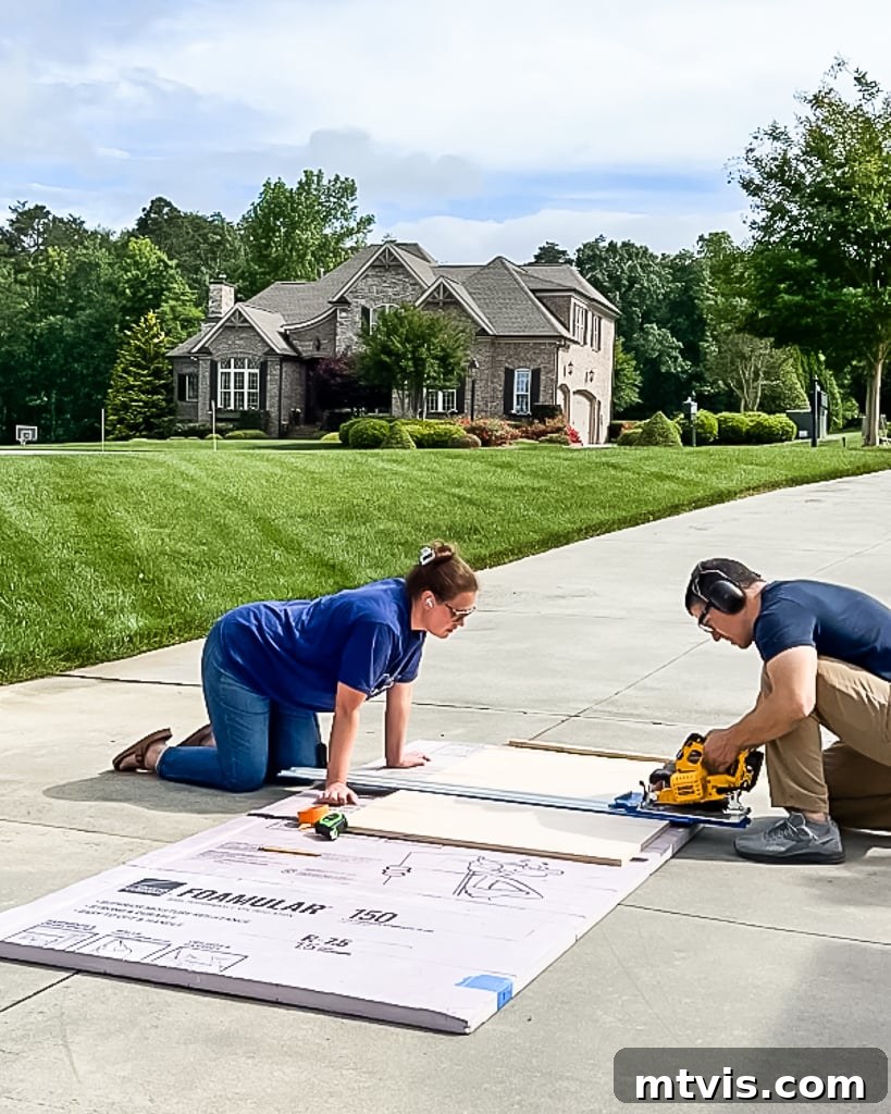 A man and woman precisely cutting a large plywood sheet using a Kreg cutting guide and a circular saw to prepare panels for a DIY dog crate.