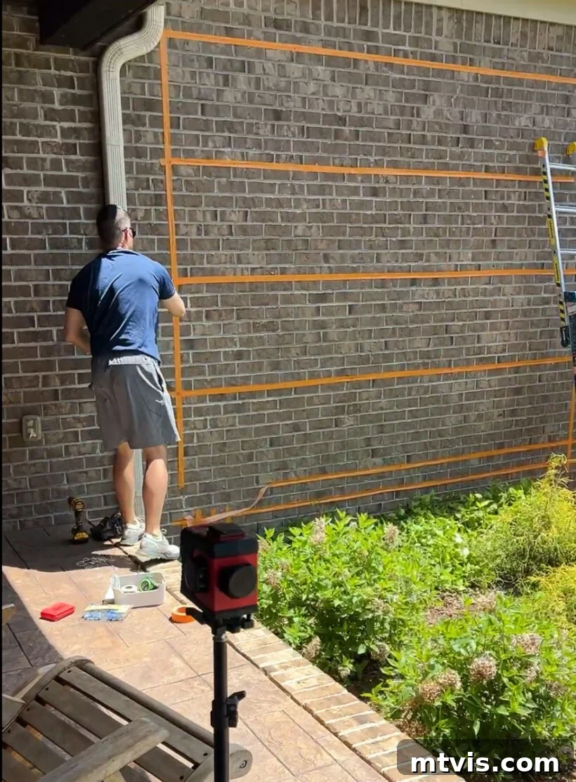 Painter's tape outlining the wire trellis pattern on a brick wall, ready for installation