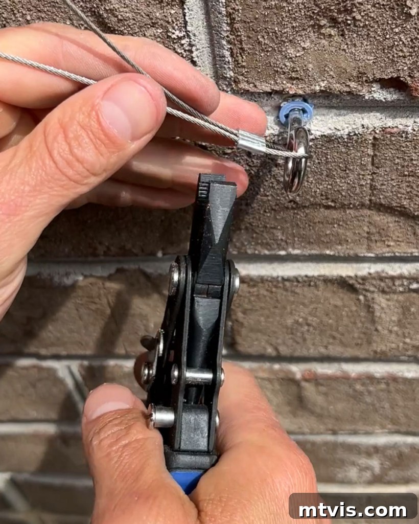Man using pliers to clamp an aluminum ferrule on a wire rope for a secure trellis attachment