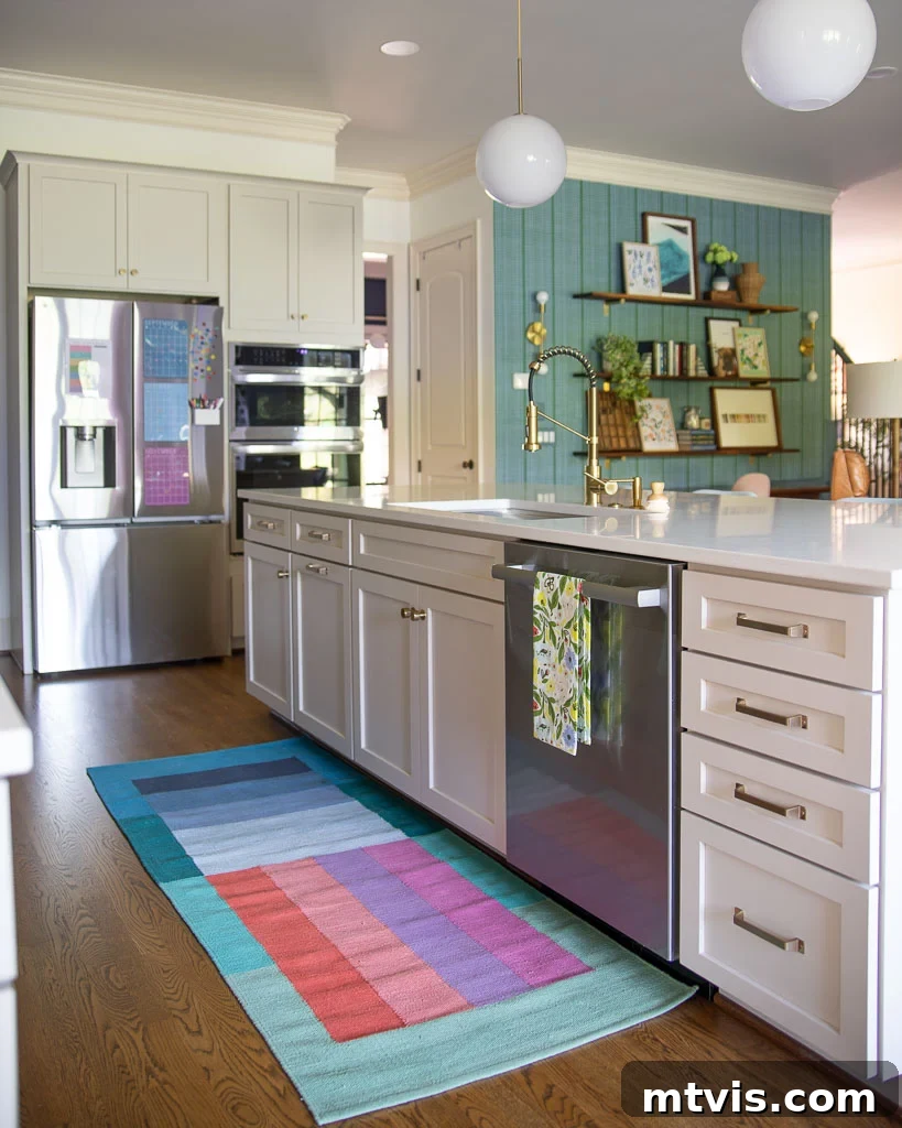 Our Kitchen Reveal: Serene Neutrals, Lively Hues 7 Photo of the new kitchen with cabinets painted Accessible Beige by Sherwin Williams, seamlessly opening to the great room with vibrant green and blue decor accents, illustrating the open concept.