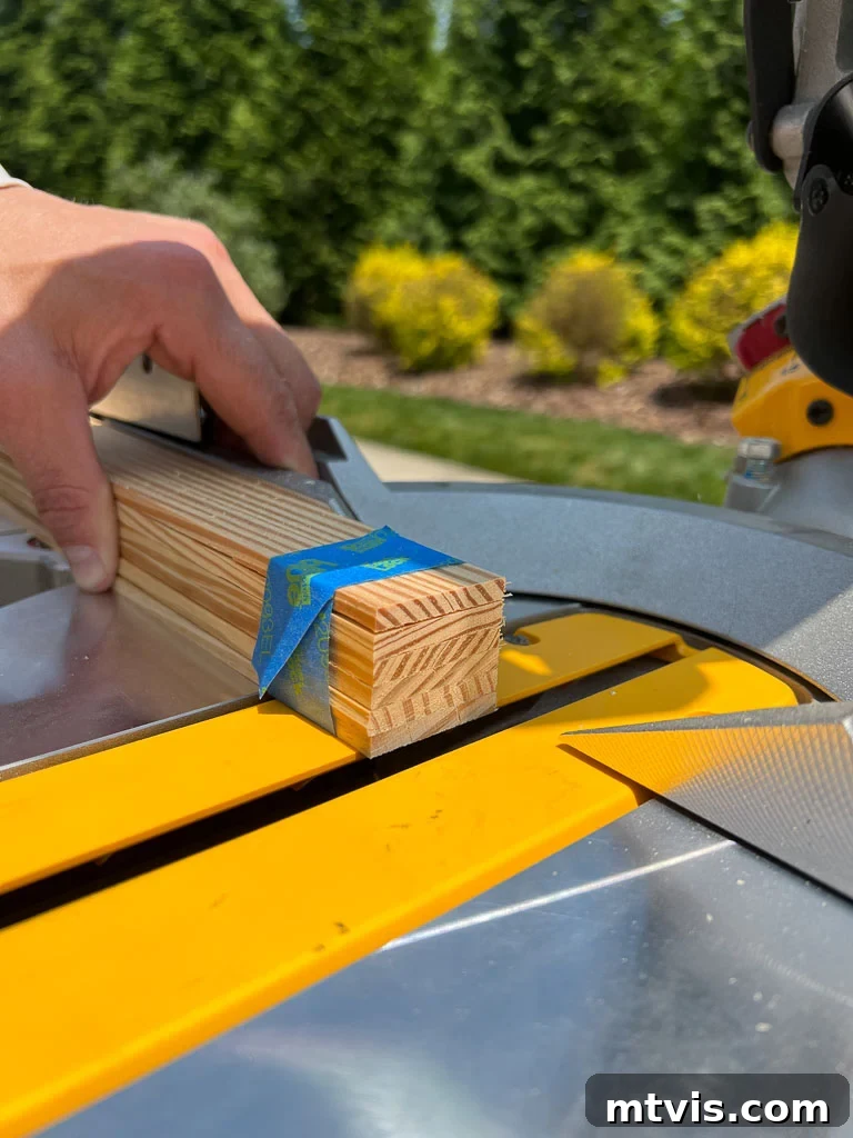 A person precisely cutting wood lattice strips to length using a compound miter saw for a DIY faux poster hanger project, ensuring accurate dimensions.