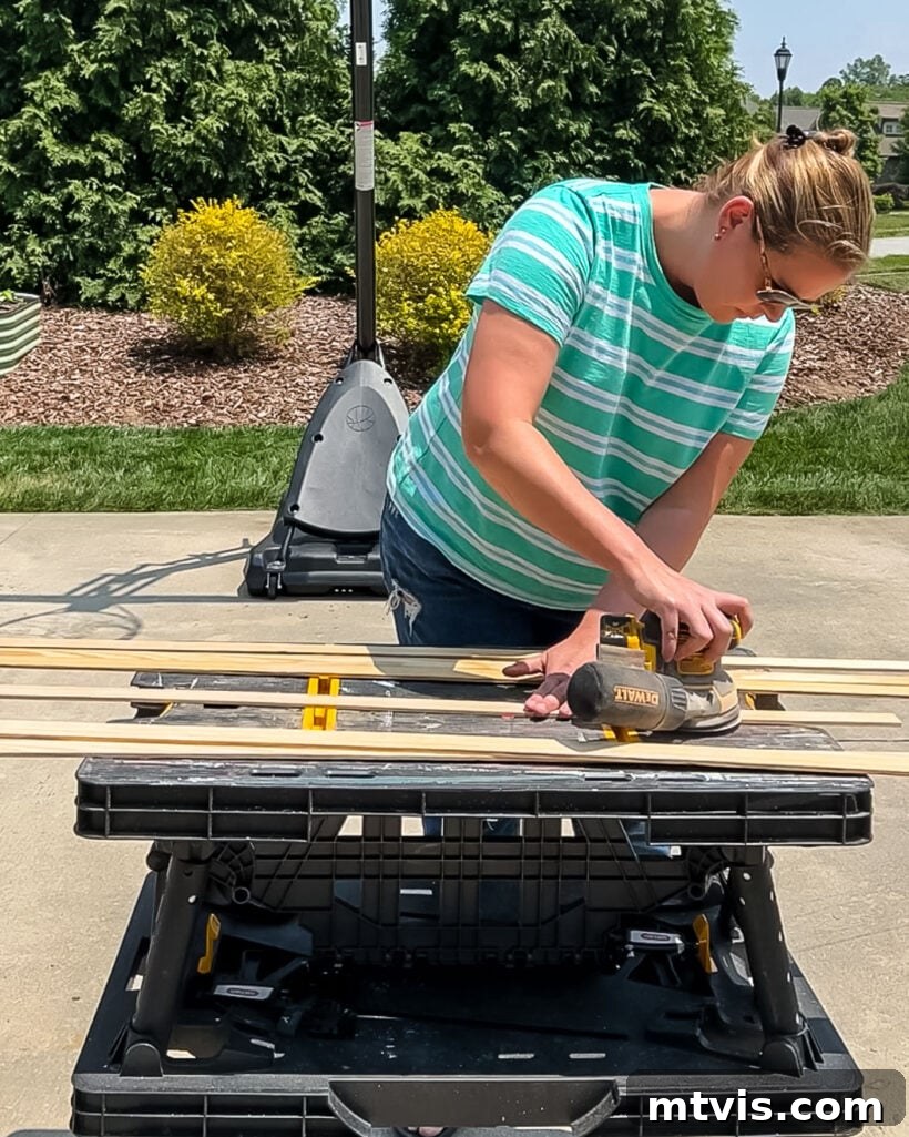 A woman carefully sanding wood lattice strips to smooth the surface, preparing them for painting or staining for DIY magnetic poster hangers.