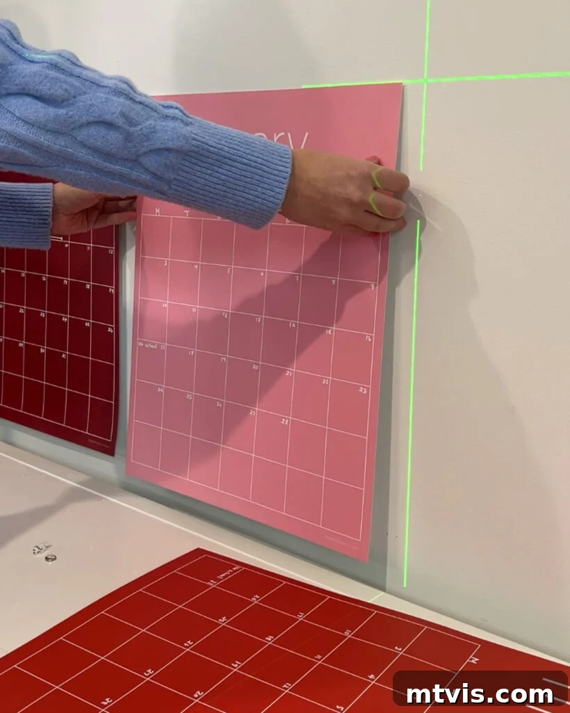 Hanging a colorful calendar poster on a wall using Command poster hanging strips, demonstrating a simple and secure method for wall display.