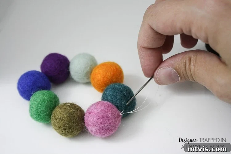 Homemade Pure Car Fragrance 6 A woman's hand pulls a needle and thread through the last two felted balls forming a circle. This craft is from