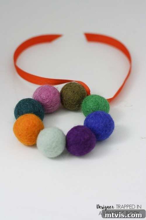 Homemade Pure Car Fragrance 10 A close-up of the finished DIY car air freshener made from felt balls, an orange ribbon and essential oils.