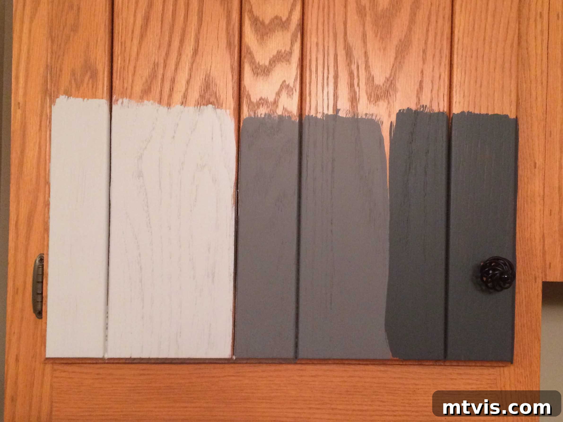 My Triple-Tested Method for Perfectly Painted Kitchen Cabinets 6 image of orangey oak kitchen cabinet door with three gray paint color samples from General Finishes Milk Paint painted on it, illustrating color testing