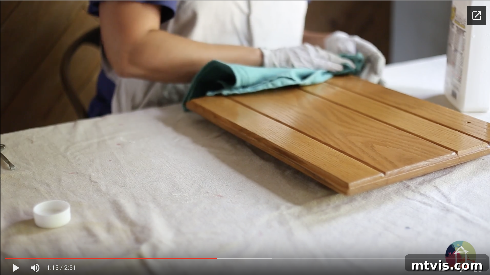 My Triple-Tested Method for Perfectly Painted Kitchen Cabinets 7 image of woman wearing latex gloves wiping down oak kitchen cabinet door with liquid deglosser, preparing surface for paint