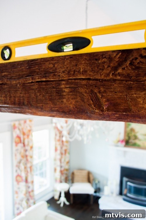 Achieve Stunning Ceilings Faux Wood Beam DIY 11 Faux wood beam being installed over a 2x4 support, with spacers ensuring a snug fit.