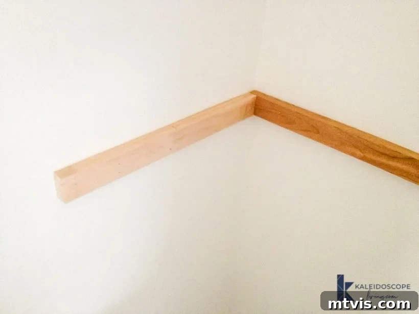 Installing wooden support pieces onto a wall in a corner nook using a brad nailer, creating the hidden framework for DIY floating shelves and a desk.