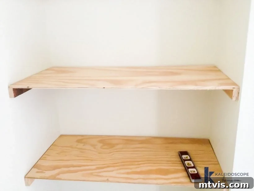 Attaching plywood to the internal support frame using a brad nailer, as part of the installation process for DIY floating shelves and a desk in a room corner.