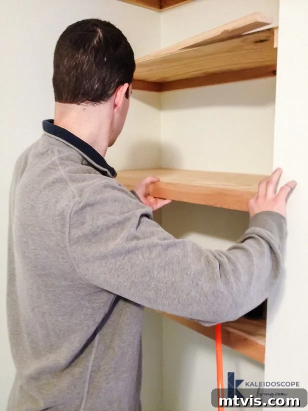 A person installing the final front support piece onto a DIY floating shelf structure in a bedroom corner, completing the hidden support framework and achieving a seamless floating look.