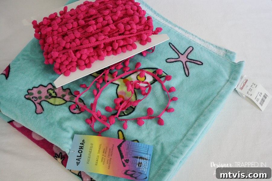 Upcycle Your Beach Towel into a Trendy Cover-Up 3 Close-up of beach towel and pom-pom trim laid out, ready for making a DIY cover-up.