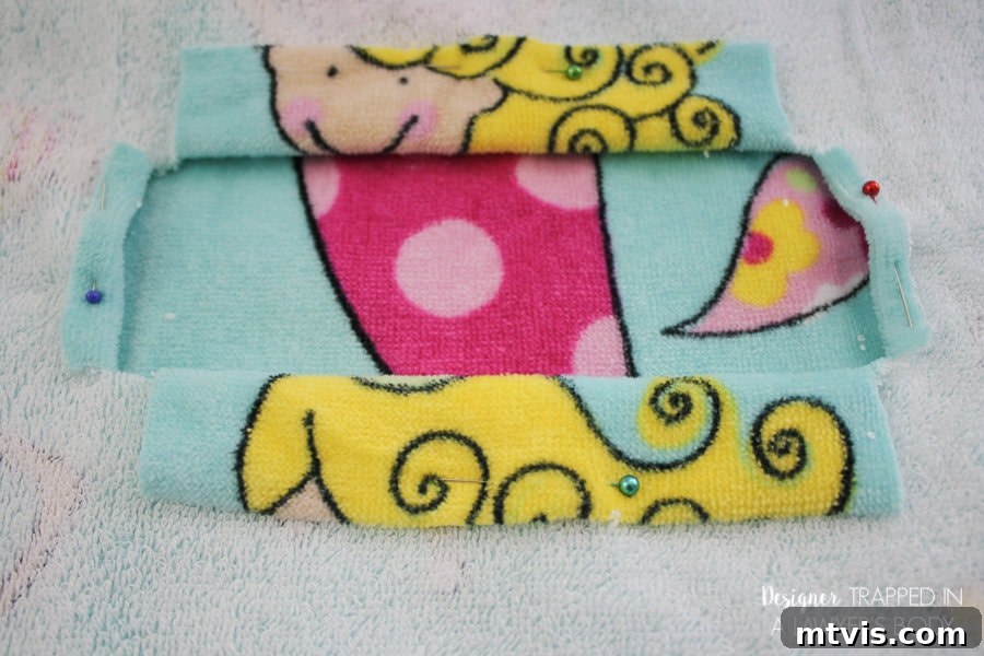 Pinning the folded edges of the head opening on a beach towel for sewing a cover-up.