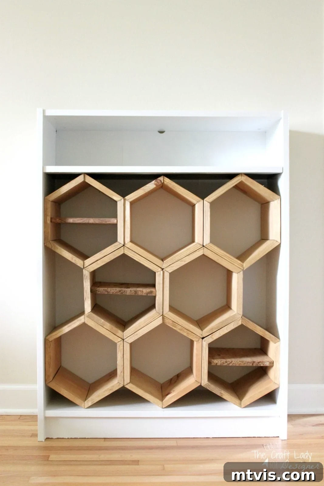 Honeycomb Shoe Organizer 16 A white bookcase has one shelf on top, but the remaining space is filled with a DIY shoe rack made from hand-cut hexagonal shoe cubbies, three of which have a wooden divider inside the honeycomb.