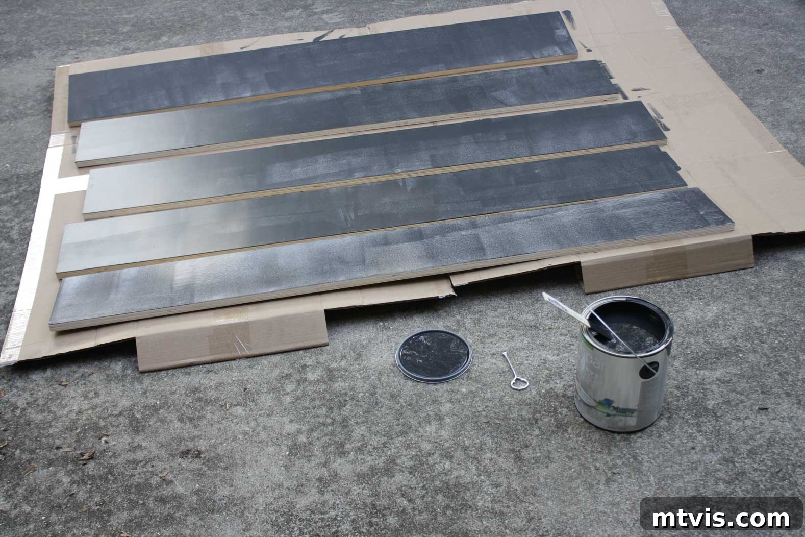 Woman painting stair risers black in a well-lit workshop, part of the DIY hardwood stairs project