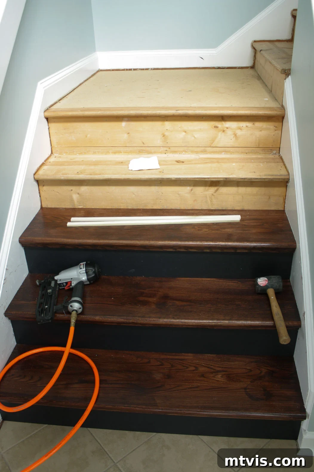 Overview of ongoing DIY hardwood stair installation, showing multiple treads and risers being fitted