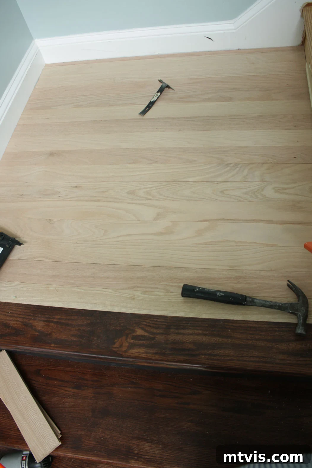 Close-up of hardwood flooring being installed on a stair landing, ensuring a seamless transition with the new treads