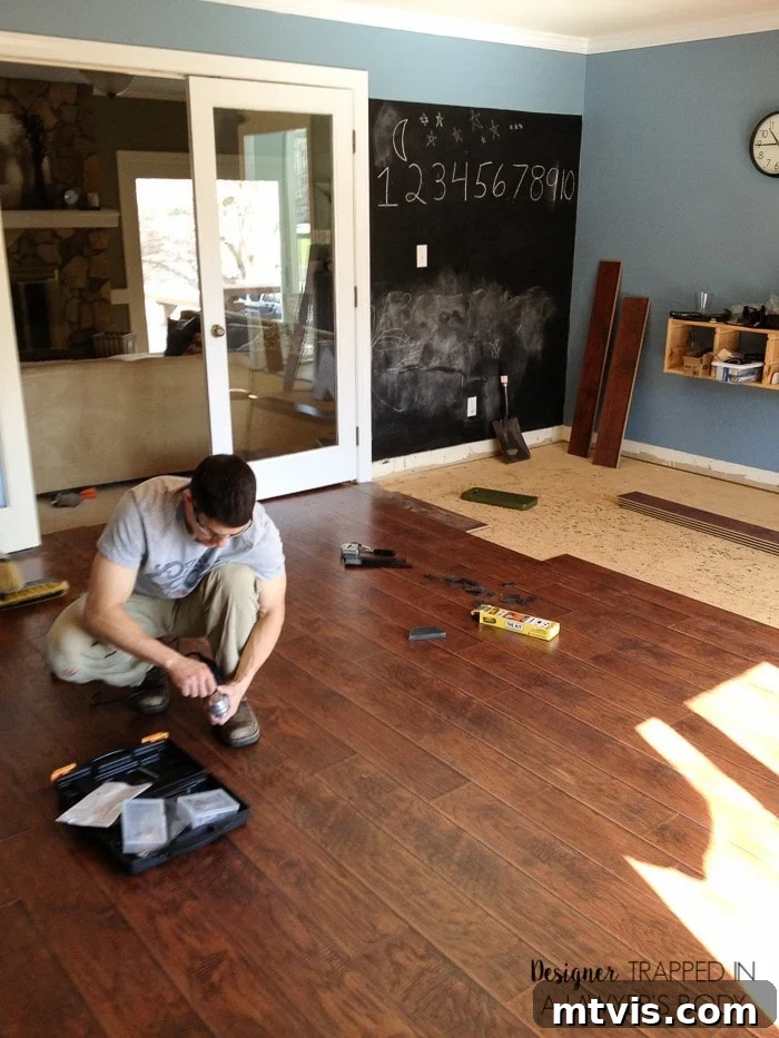 How Laminate Flooring Transformed Our Living Space 5 Detail of laminate planks being installed, showcasing the click-and-lock system for easy DIY flooring.