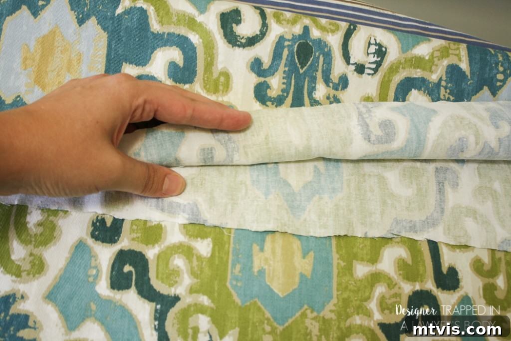 Carefully cutting the folded fabric to create two identical curtain panels for your DIY project.