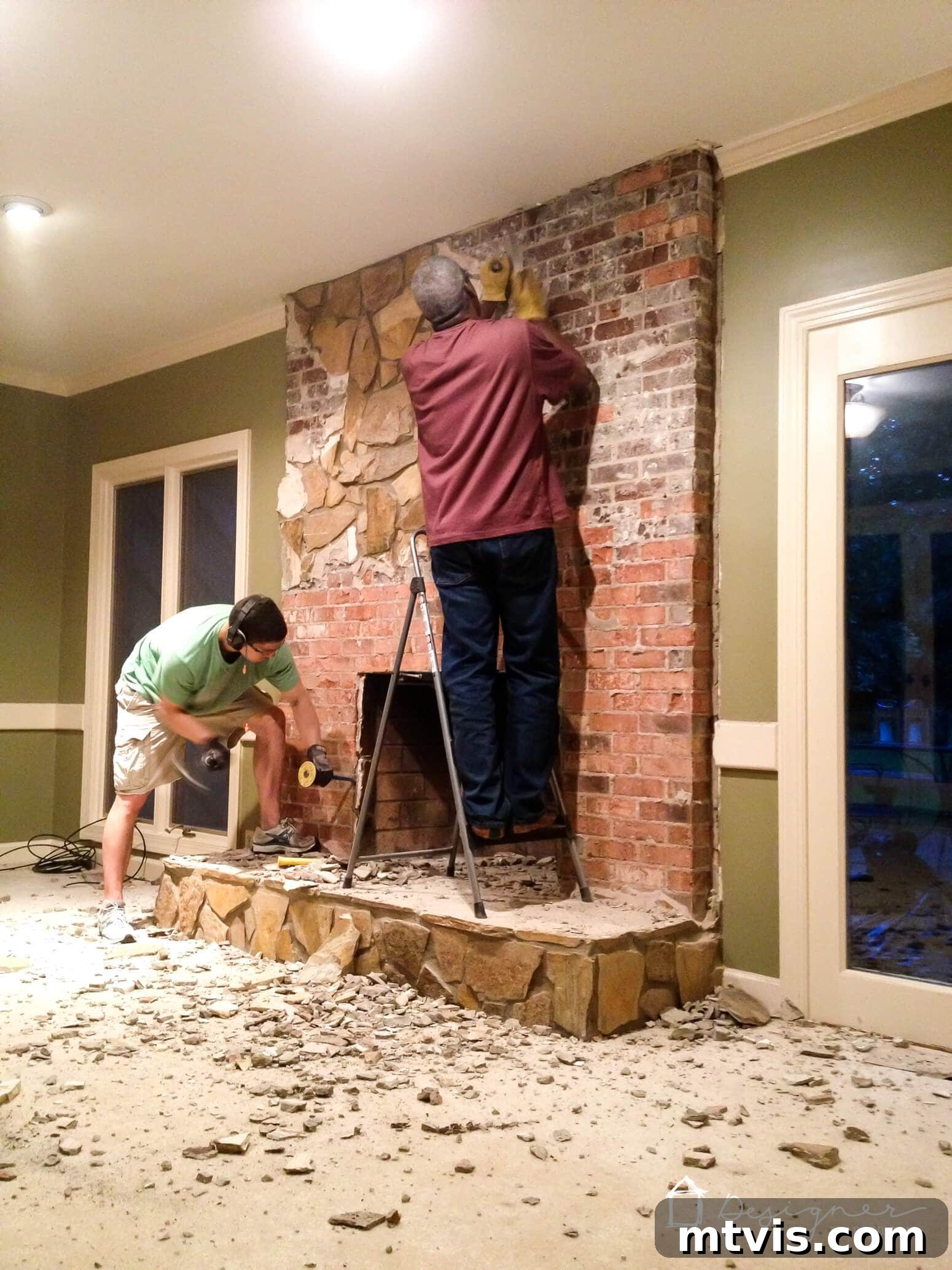 Stylish Concrete Fireplace Build for Under 100 4 Two men demolishing an old fireplace facade to prepare for a concrete overlay. The process reveals the underlying brick structure.
